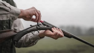 A close-up of hunter man charges the cartridge on rifle gun in forest.