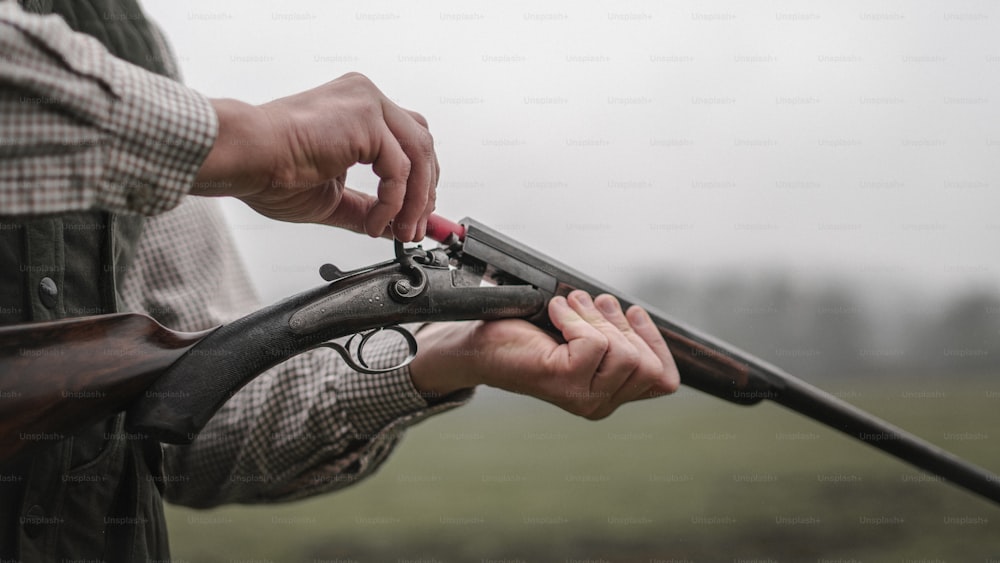 Un primer plano de un cazador carga el cartucho de la pistola de rifle en el bosque.