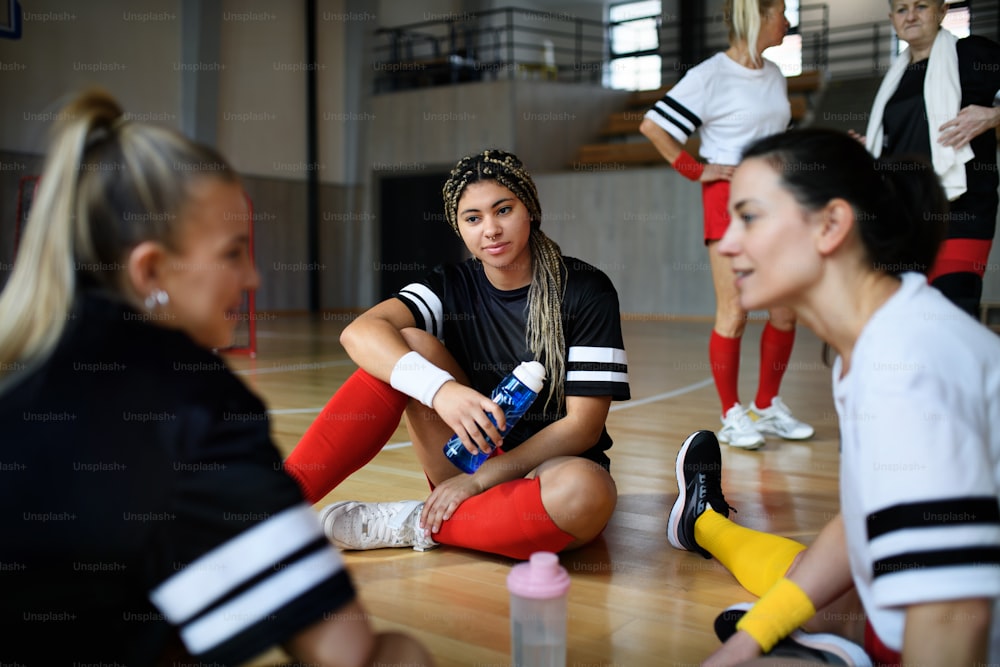 젊은이와 노인 여성 그룹, 체육관에 앉아 경기 후 이야기하는 스포츠 팀 선수들.