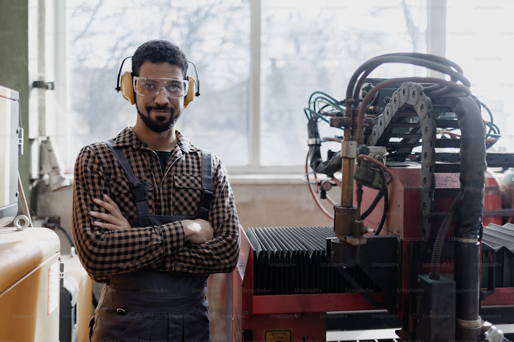 A portrait of heavy industry worker with safety headphones and in industrial factory