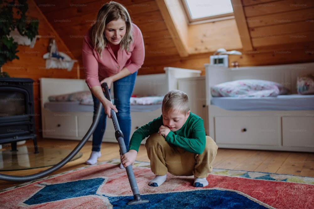 ダウン症の男の子と母親が自宅で掃除機をかける