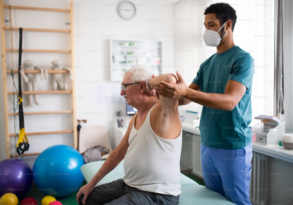 A young physiotherapist exercising with senior patient in a physic room.