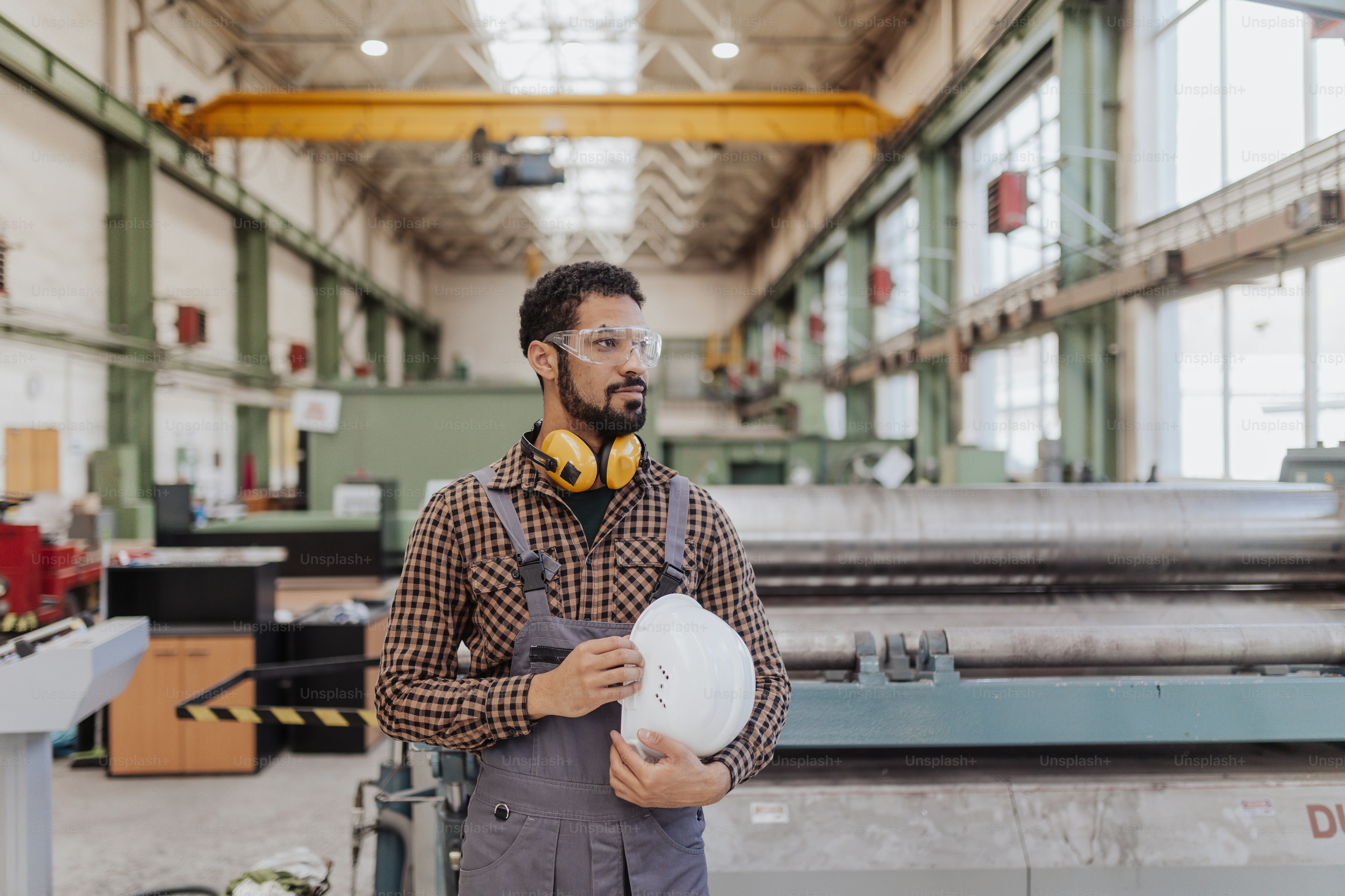 Un operaio dell'industria pesante con cuffie di sicurezza ed elmetto in una fabbrica industriale