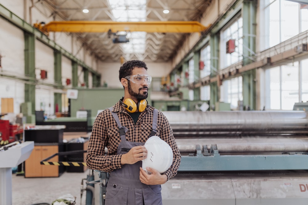 A heavy industry worker with safety headphones and hard hat in industrial factory