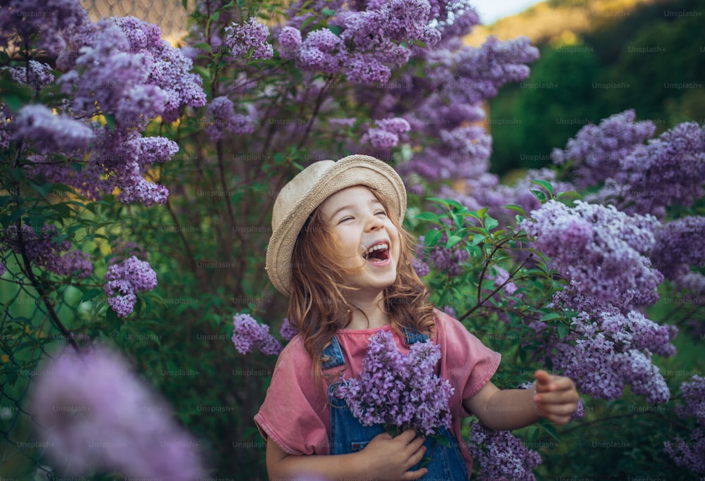 Um retrato de uma garotinha alegre na natureza florescendo prado lilás-púrpura.