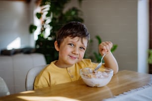 Un retrato de un niño sonriente disfrutando del desayuno en la cocina de su casa