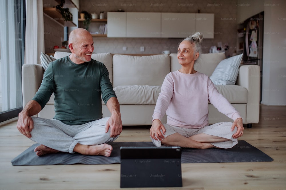 A senior couple doing relaxation exercise together at home.