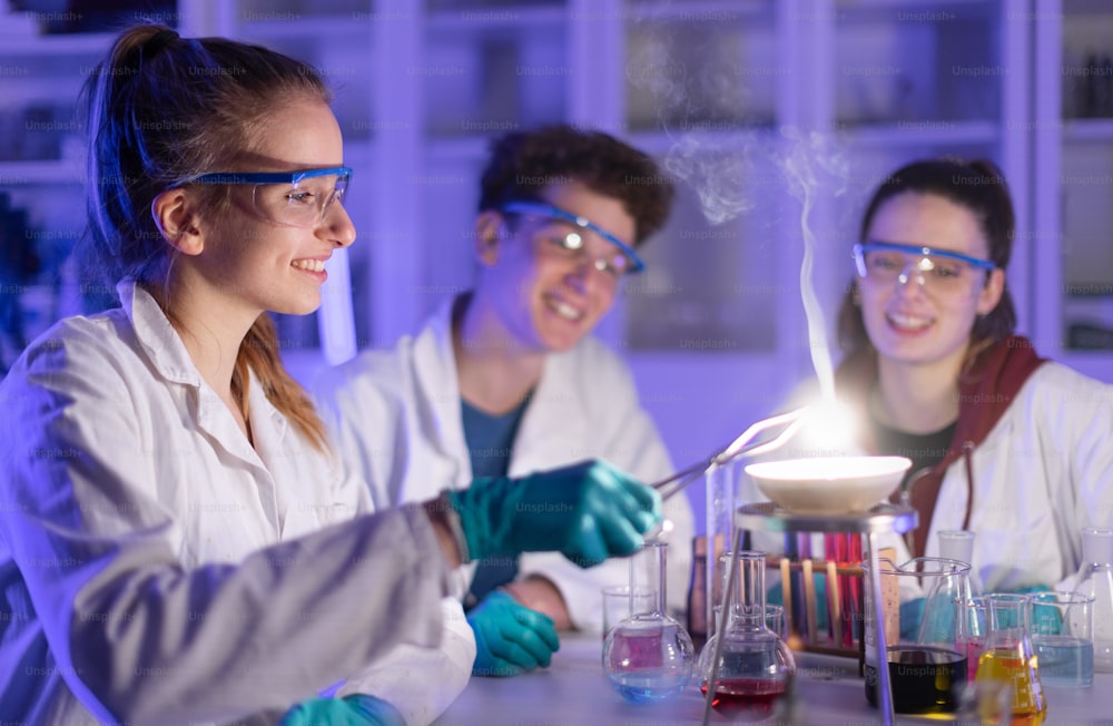 Estudiantes de ciencias emocionados haciendo un experimento químico en el laboratorio de la universidad.