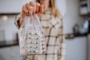 La mano de una mujer sosteniendo pastillas caducadas listas para reciclar.