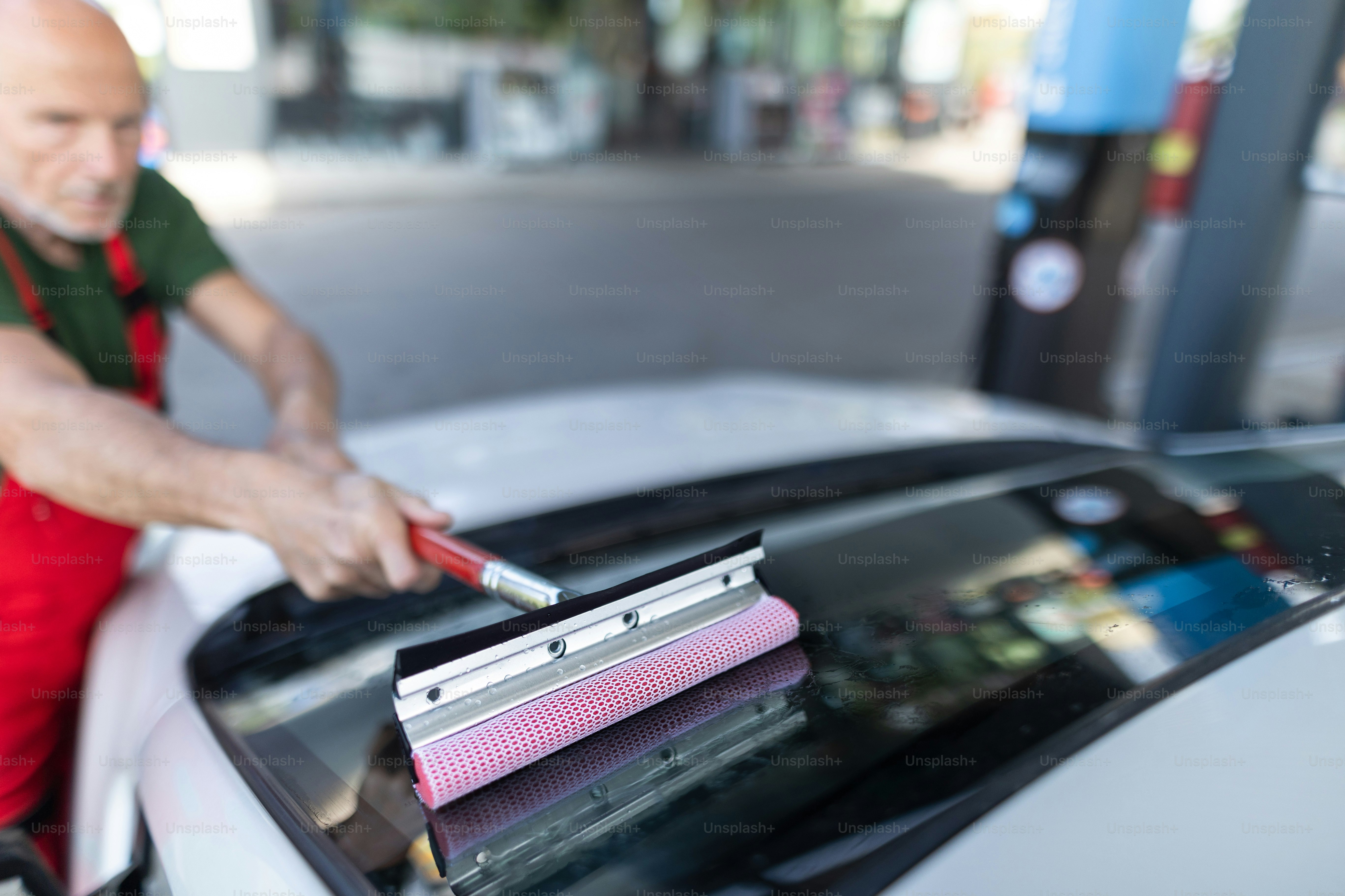Senior worker washing a car window at gas station. photo ...
