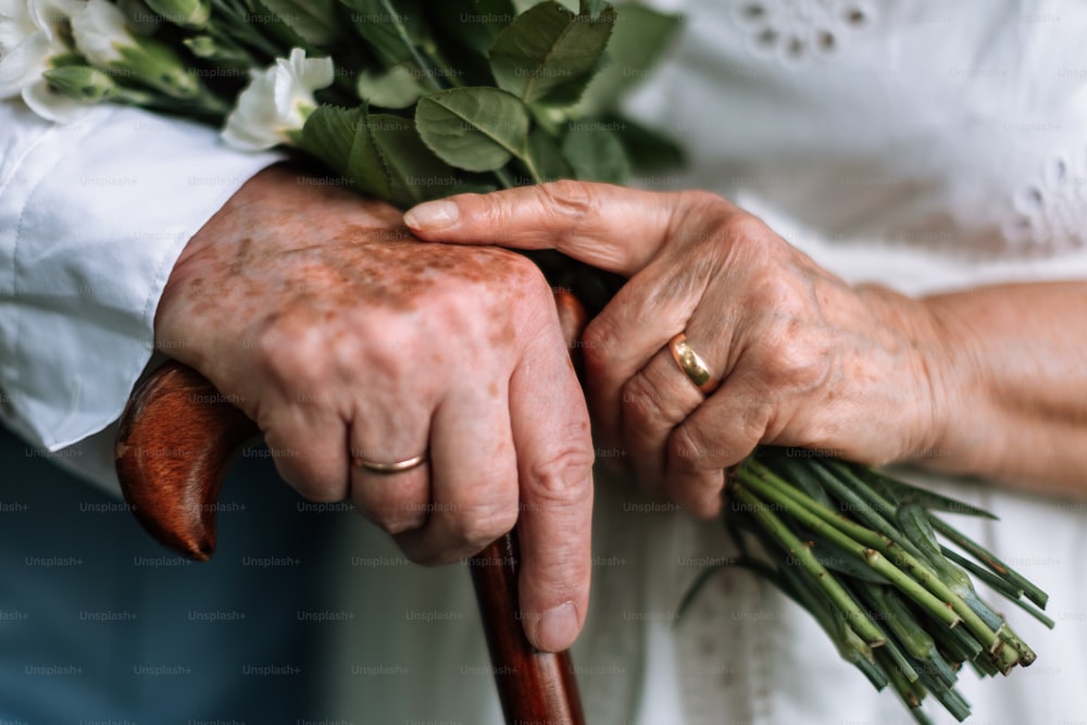 Gros plan sur les mains des personnes âgées avec des alliances en or pendant leur mariage.