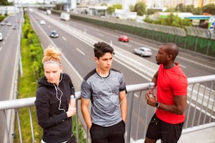 Beautiful young runners in the city standing on a bridge resting.