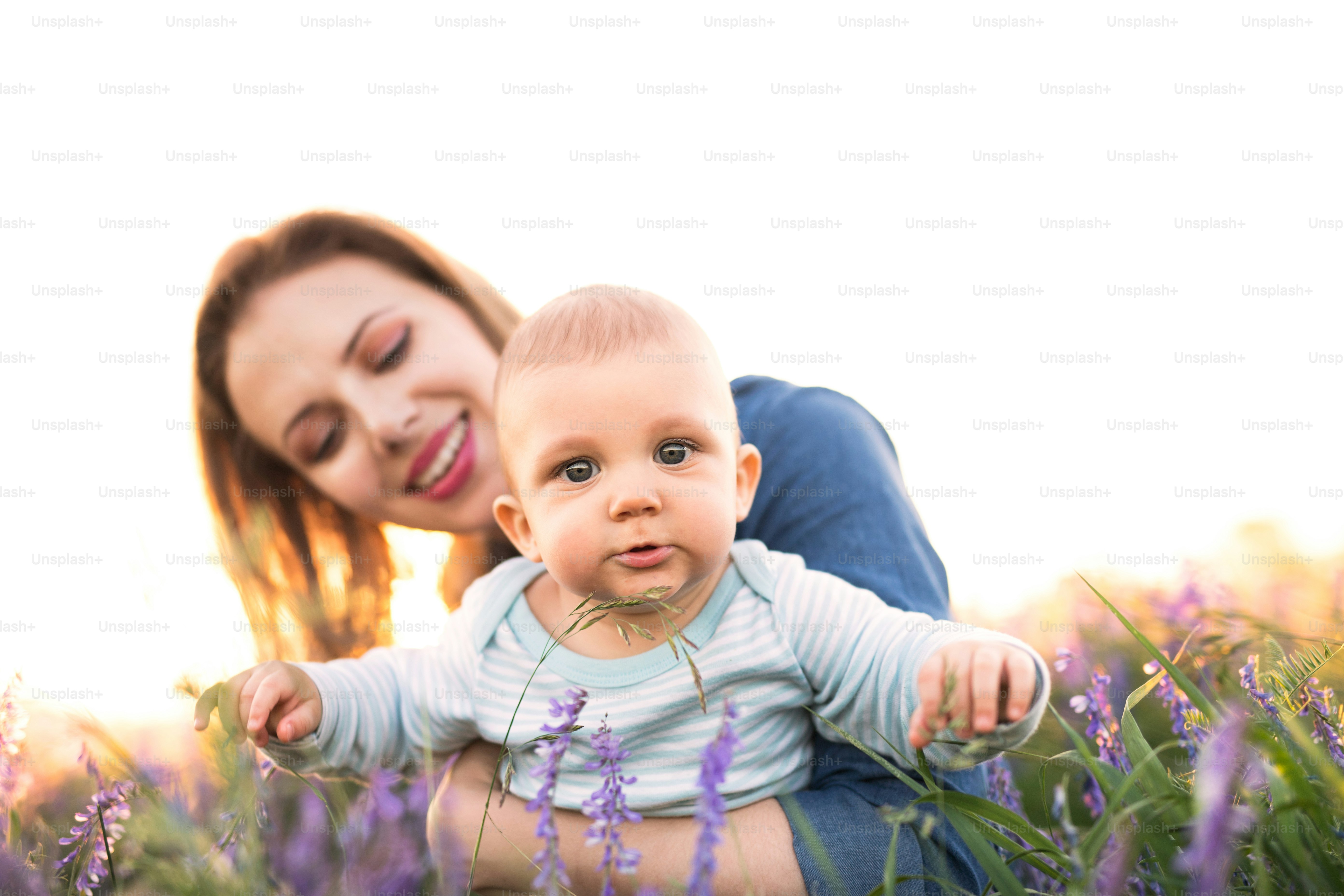 Ibu muda yang cantik menggendong bayi laki-lakinya yang masih kecil di pelukan di luar ruangan di alam di ladang lavender.