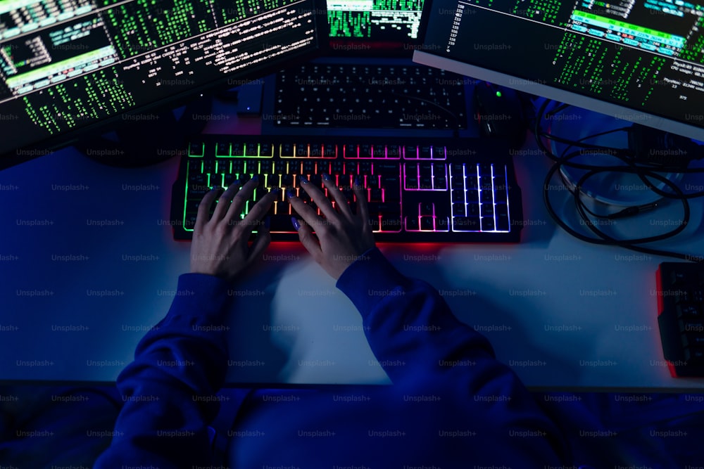夜の暗い部屋でキーボードコンピュータを握る女性ハッカーのクローズアップ、サイバー戦争のコンセプト。ハイアングルビュー。