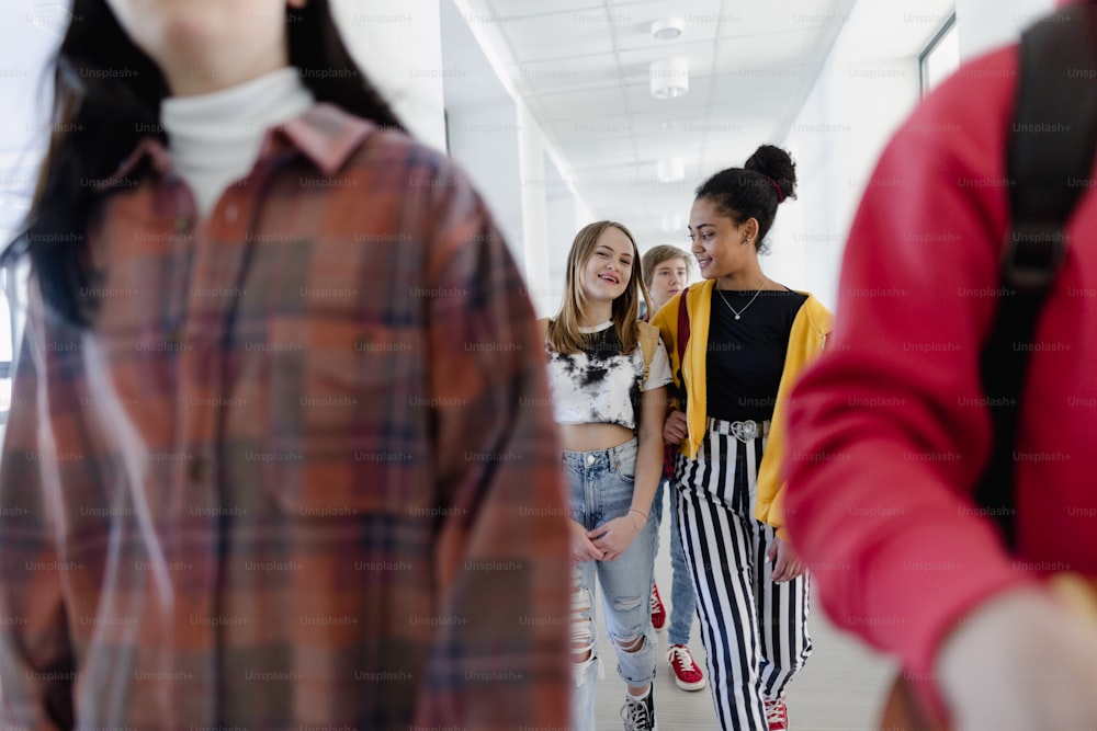 Young high school students walking in a corridor at school, back to school concept.