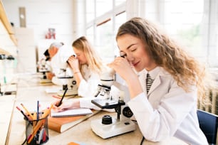 Schöne Gymnasiasten mit Mikroskopen im Labor. Oberlehrer für Biologie.
