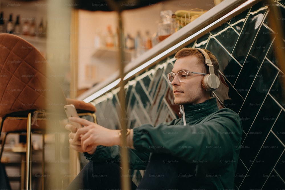 Un jeune homme avec des écouteurs profite d’écouter de la musique à l’intérieur dans un café.