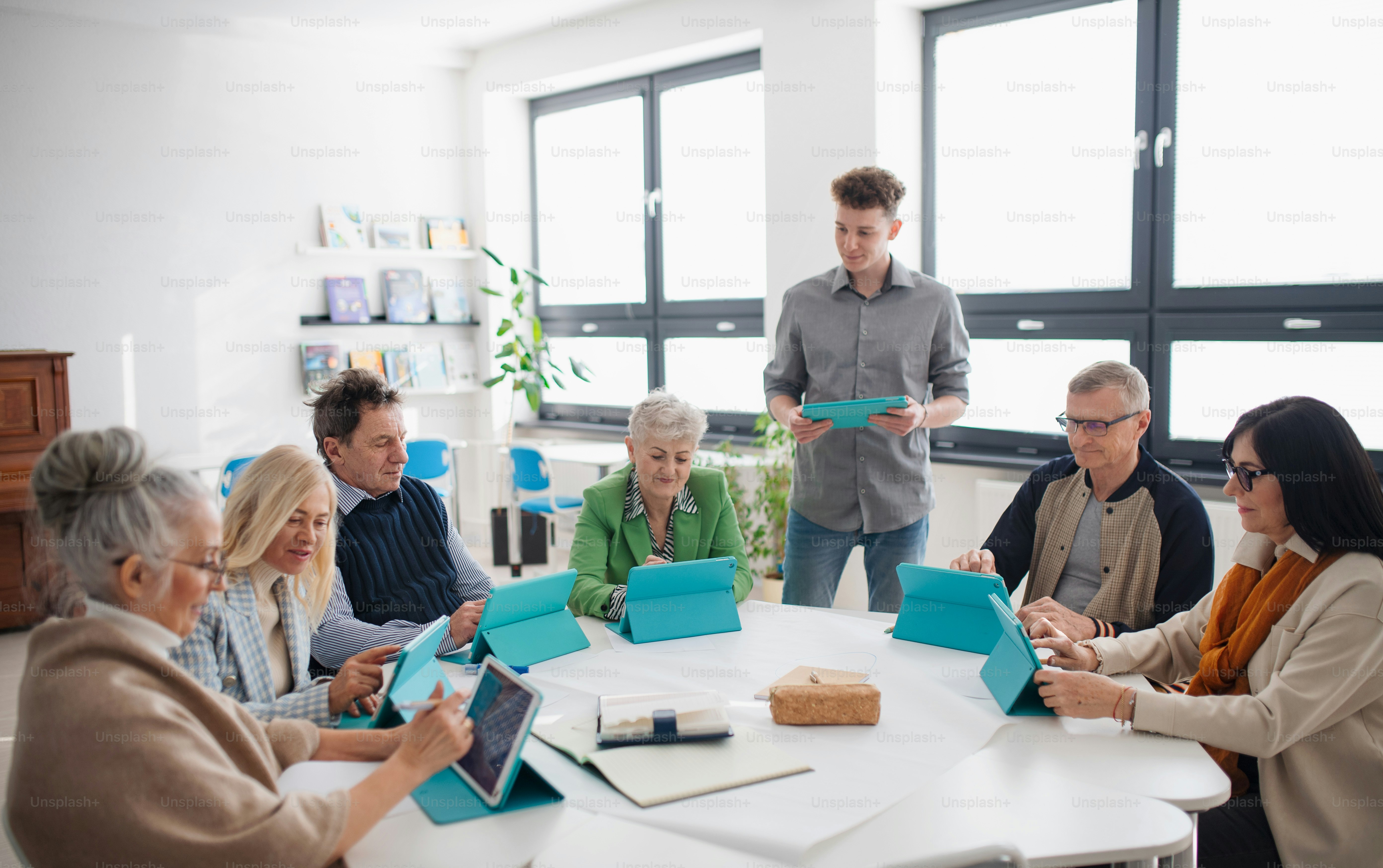 Un gruppo di anziani che frequentano la classe di informatica in un centro comunitario con insegnante