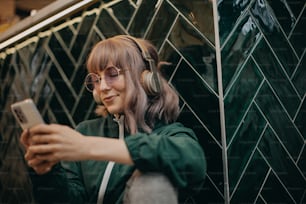 Uma jovem mulher usando fones de ouvido e gostando de ouvir música dentro de casa.