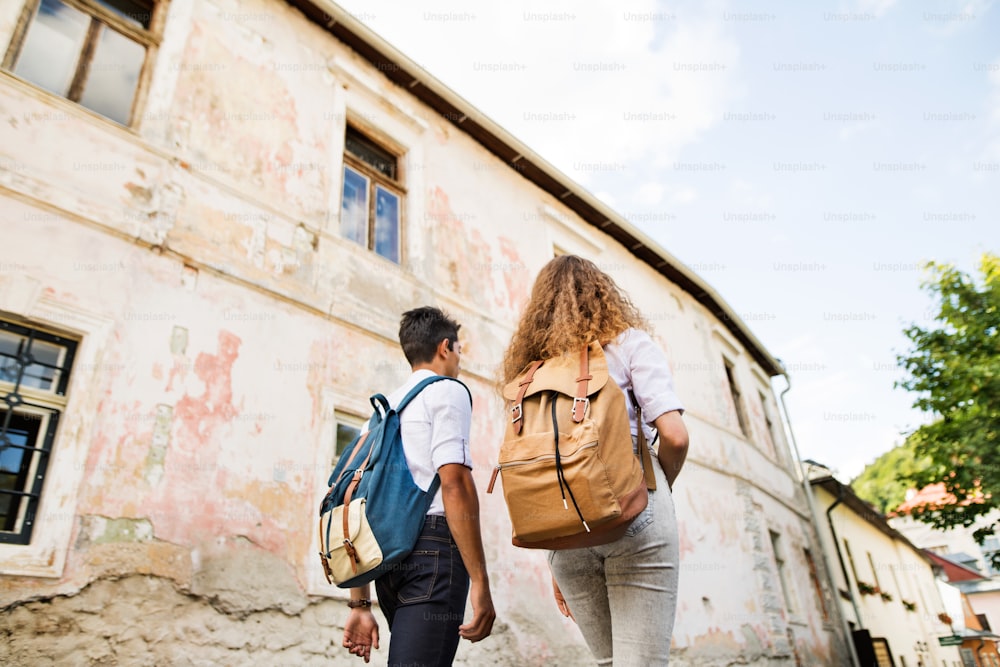 Two beautiful young tourists with backpacks in the old town. Rear view.