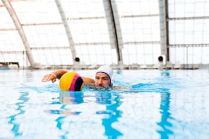 Water polo player in a swimming pool. Man doing sport.