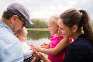 Heureuse jeune famille passant du temps ensemble à l’extérieur dans la nature verdoyante au bord du lac. Heure d'été.
