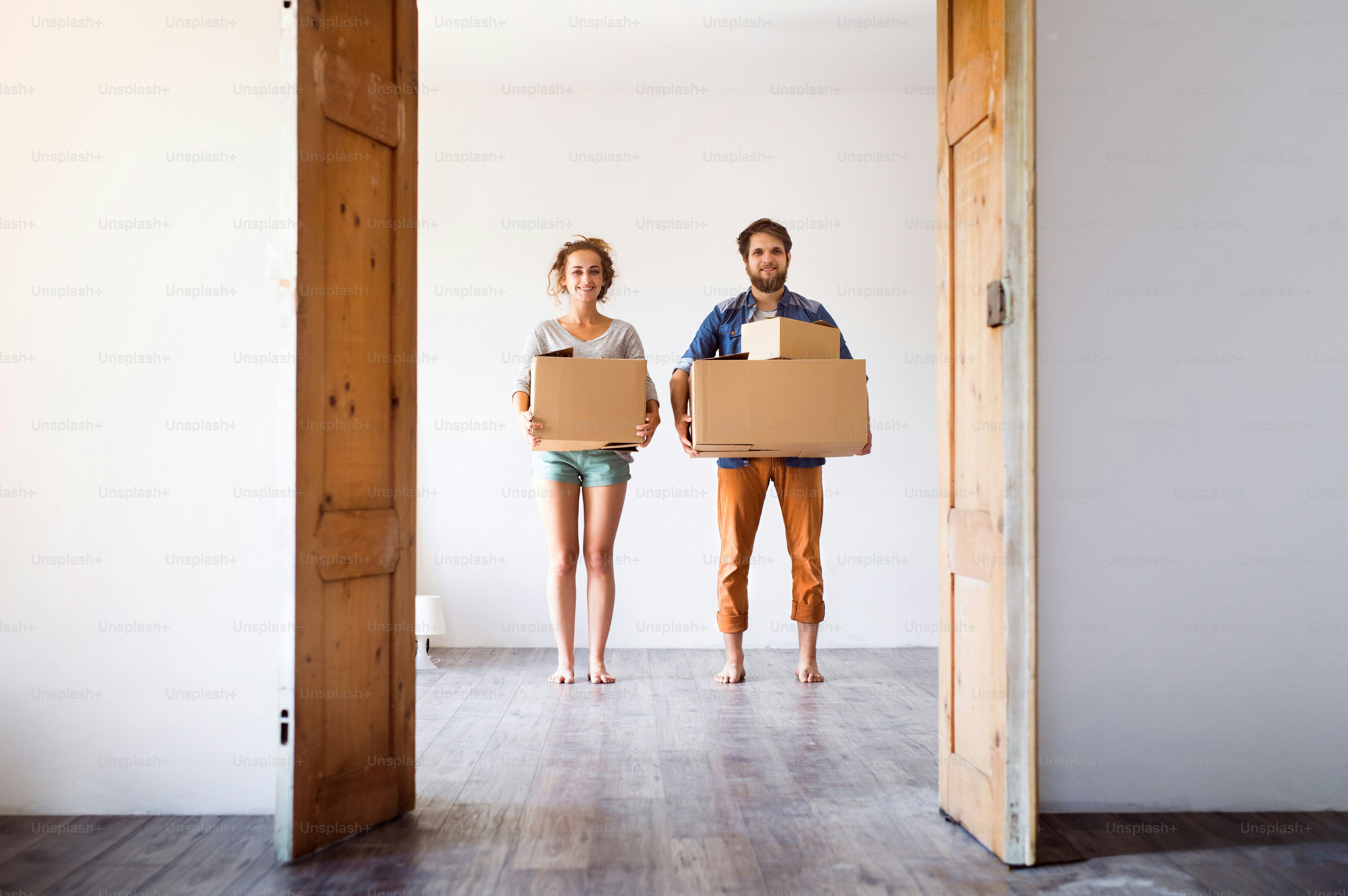 Young married couple moving in new house, holding big cardboard boxes ...