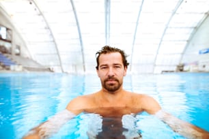 Young man swimming in indoor swimming pool. Man doing sport.
