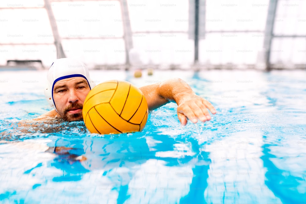 Jogador de polo aquático em uma piscina. Homem fazendo esporte.