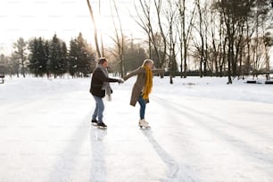 Bela mulher sênior e homem na natureza ensolarada do inverno patinando no gelo.