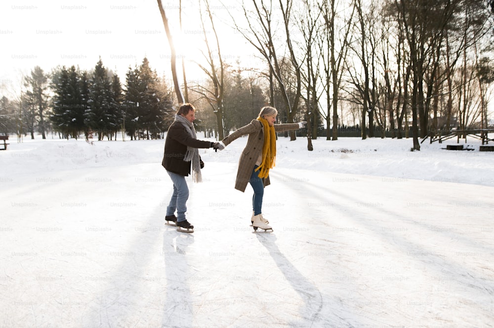 Belle femme et homme âgés dans la nature ensoleillée de la nature hivernale patinage sur glace.