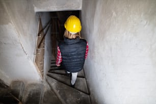 Female worker on the construction site. Beautiful young woman working on the building site. Rear view.