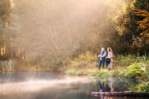 Pareja de ancianos activa pescando en el lago. Una mujer y un hombre en una hermosa naturaleza otoñal a primera hora de la mañana.