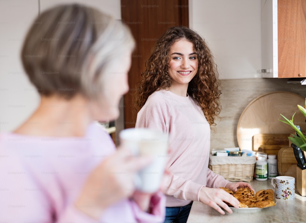 Une adolescente avec sa mère ou sa grand-mère dans la cuisine à la maison. Concept de famille et de générations.