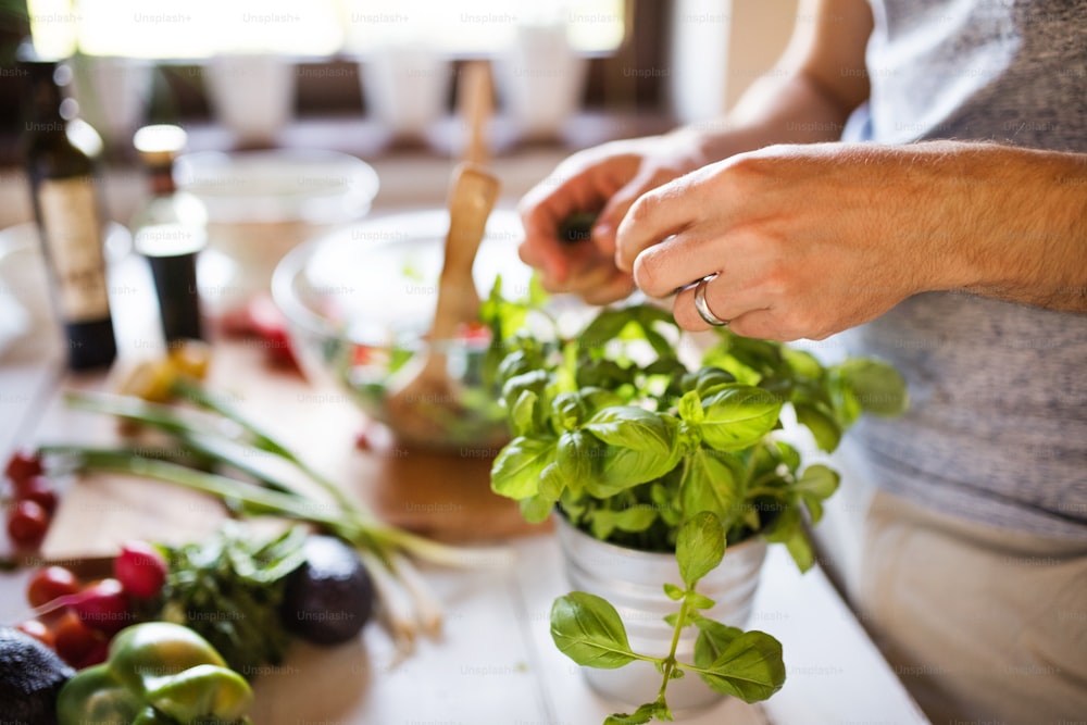 Unrecognizable young man cooking. A man making a vegetable salad.