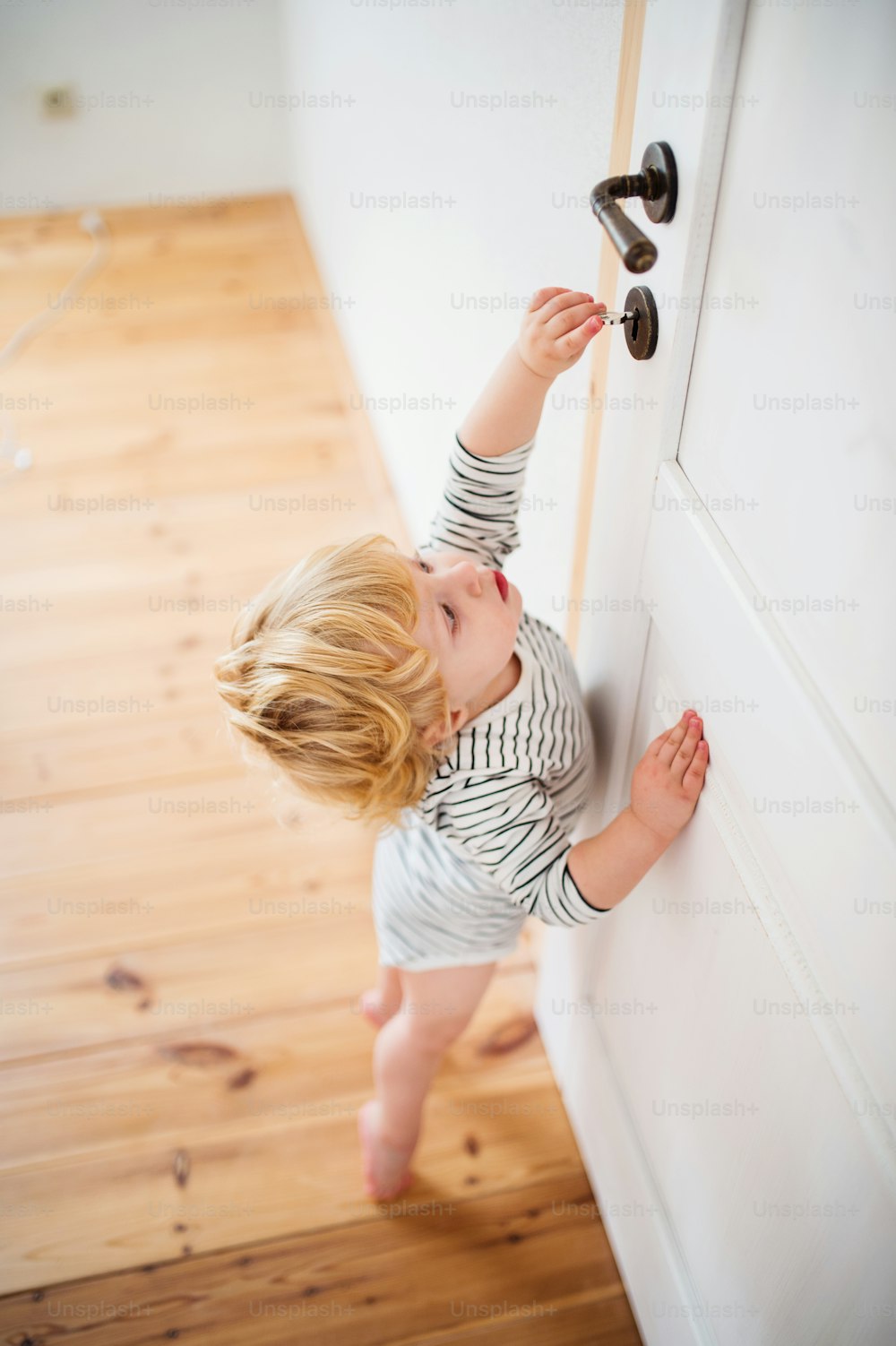 Cute toddler child locking door. Domestic accident. Dangerous situation at home.