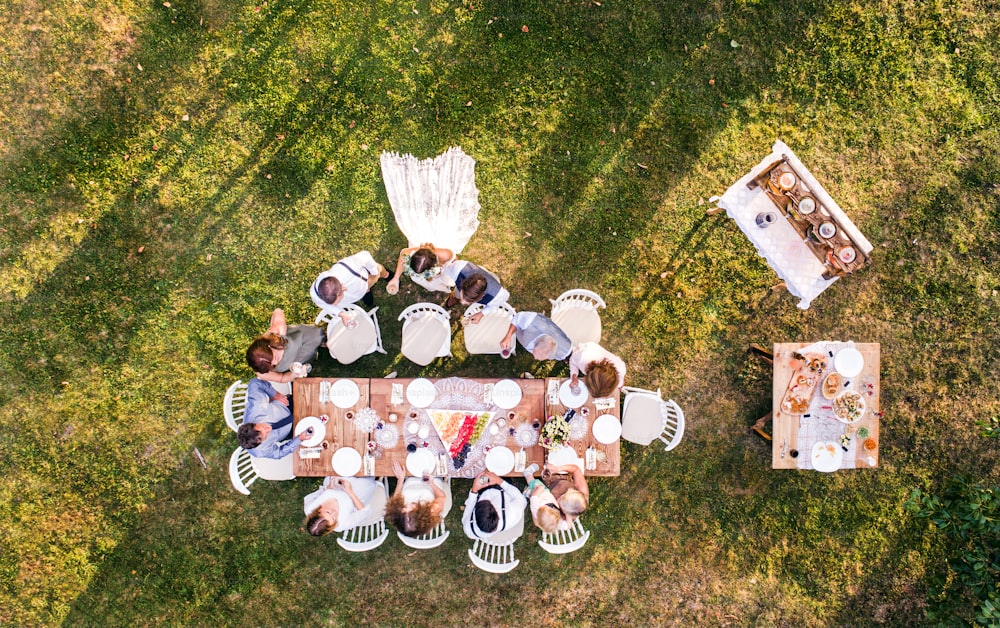 裏庭での結婚披露宴。新郎新婦と家族がテーブルを囲み、手を振っている。航空写真。