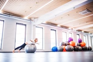 Young beautiful woman doing exercise with a fitball in a gym.