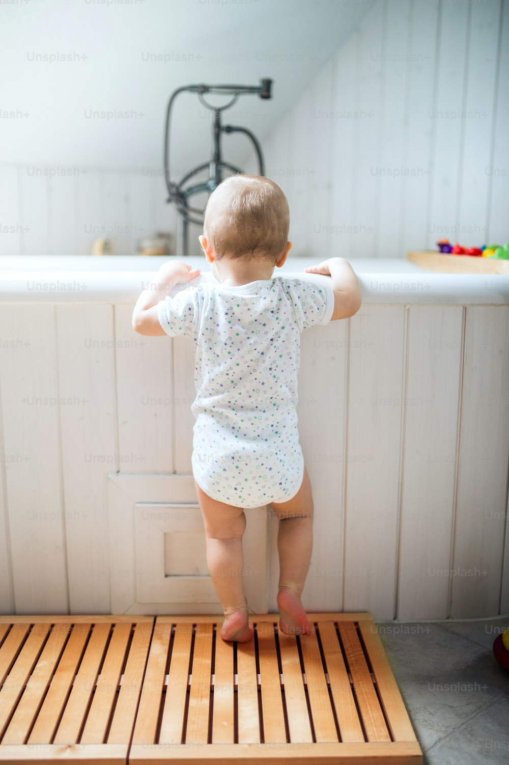 Un bambino in piedi al bagno nel bagno di casa. Retrovisore.