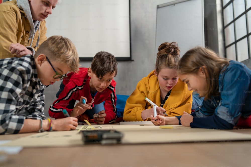 Un grupo de niños felices con su profesor de ciencias con juguetes eléctricos y robots en el aula de robótica