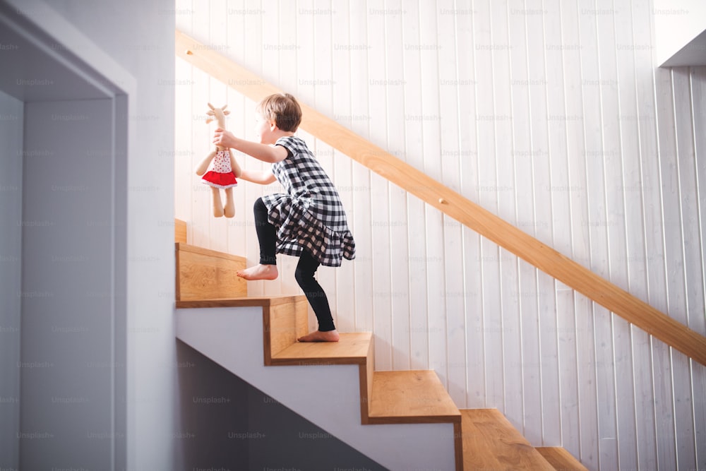 A small child with a soft toy walking up the stairs. Copy space.