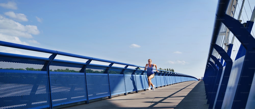 A mid adult woman running outdoors in city, healthy lifestyle concept.