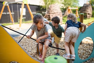 Un gruppo di piccoli bambini della scuola materna che giocano all'aperto nel parco giochi.