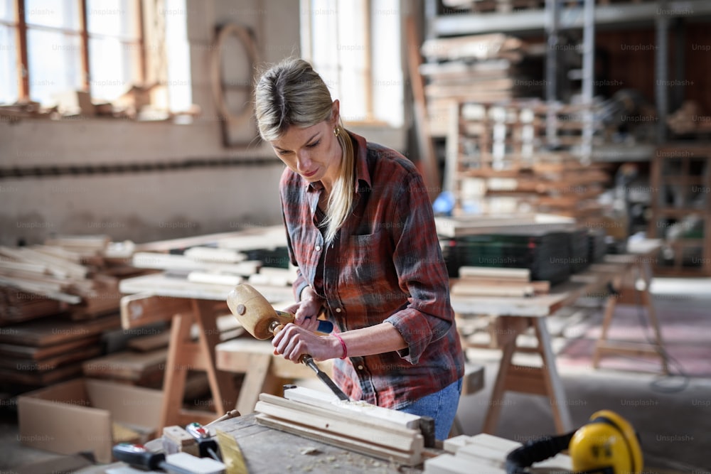 Un retrato de una carpintera trabajando en su producto en el interior de un taller de carpintería.