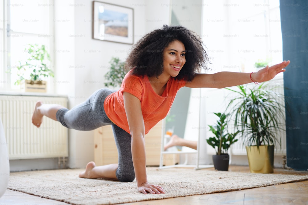 Happy young woman indoors at home, doing exercise. Sport concept.