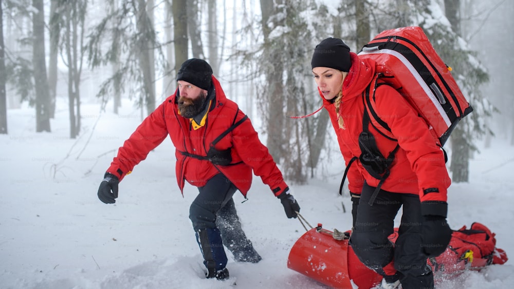Sanitäter der Bergwacht sorgen im Winter im Freien im Waldeinsatz, Verletzte auf einer Trage.