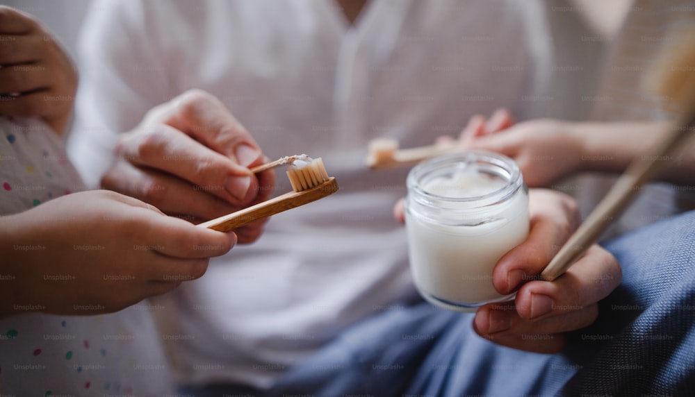 Les mains d’un père méconnaissable avec deux jeunes enfants qui se brossent les dents à l’intérieur à la maison, concept de mode de vie durable.