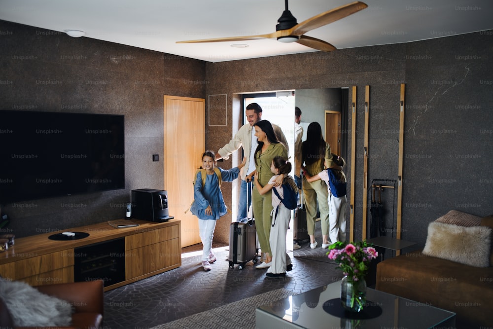 Una giovane famiglia felice con due bambini enetring camera in hotel di lusso, vacanze estive.