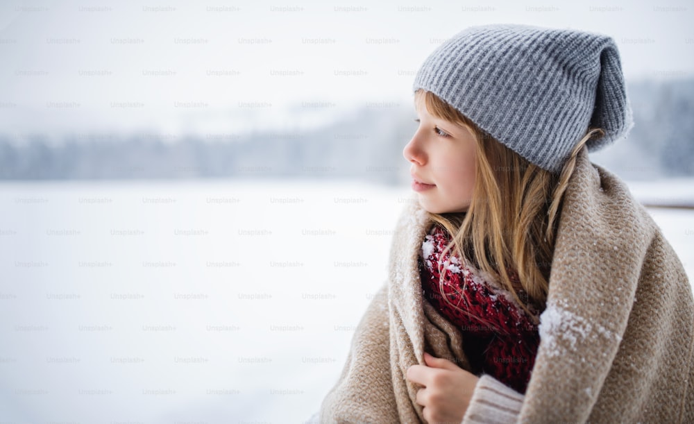 A portrait of preteen girl outdoors in winter nature, copy space.
