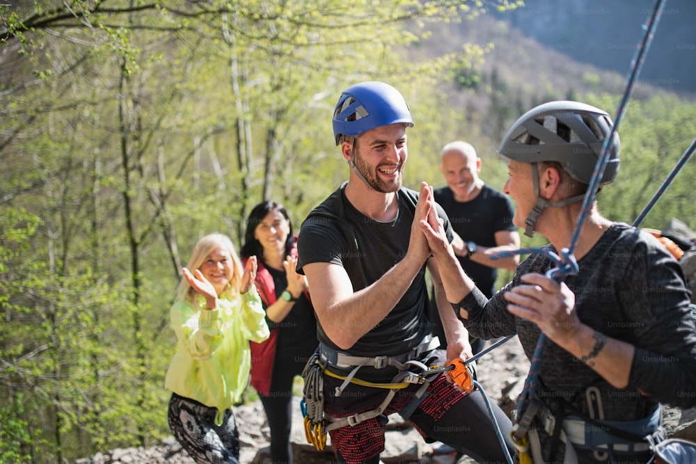 Un grupo de personas mayores con instructor de escalada de rocas al aire libre en la naturaleza, estilo de vida activo.